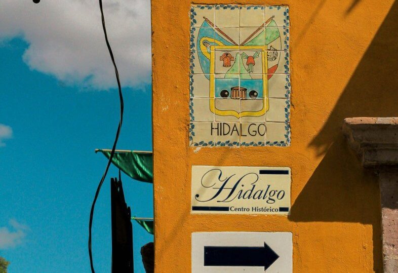 Vibrant street scene in Dolores Hidalgo with historic signage and architecture.