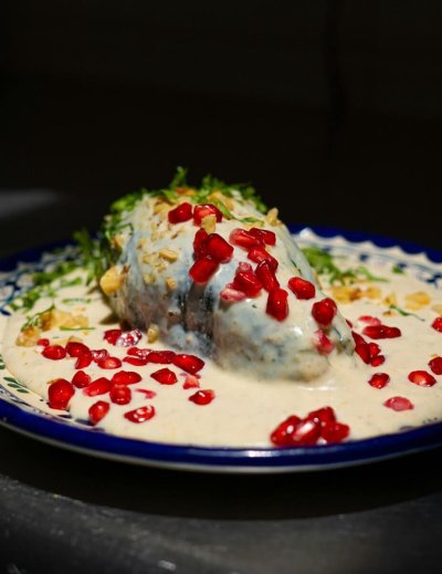 Delicious Mexican Chiles en Nogada garnished with pomegranate seeds on a decorative plate.