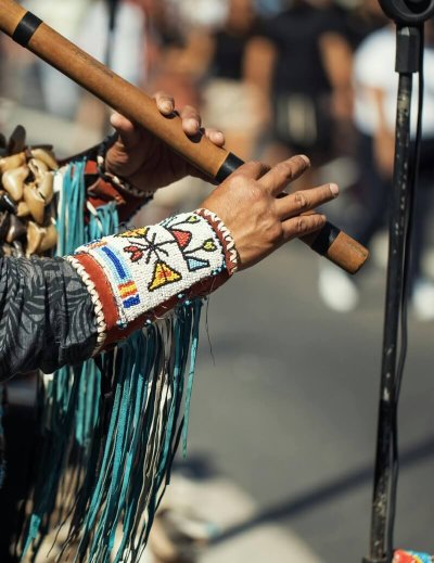 Street performer in cultural attire playing a traditional flute outdoors. Authentic and vibrant.