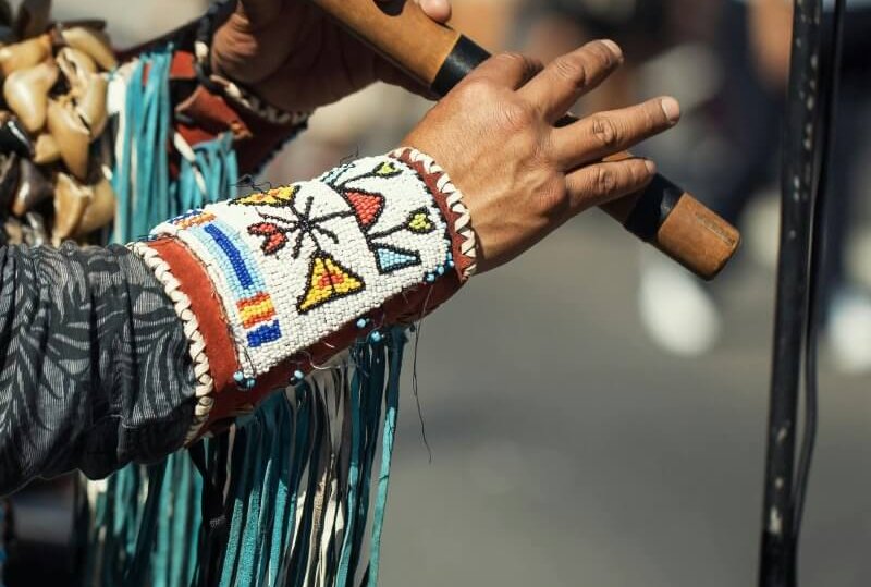 Street performer in cultural attire playing a traditional flute outdoors. Authentic and vibrant.