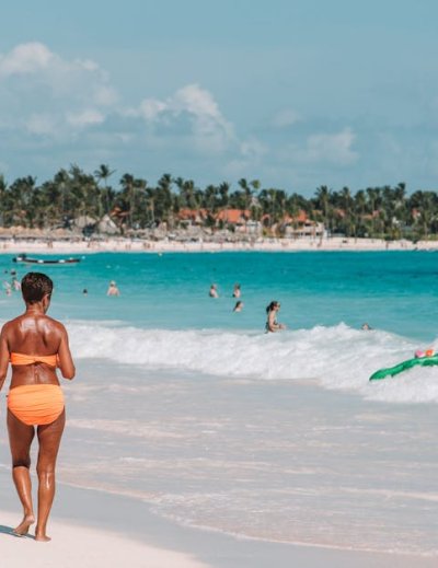 Woman walking on white sand beach with turquoise water and palm trees in Punta Cana