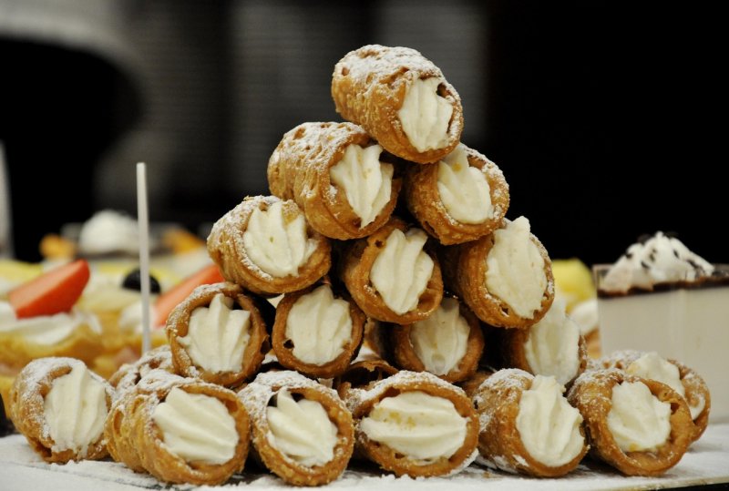 Stack of traditional Sicilian cannoli filled with ricotta cream and dusted with powdered sugar