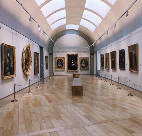 Elegant museum gallery with classical paintings in gold frames and skylight ceiling