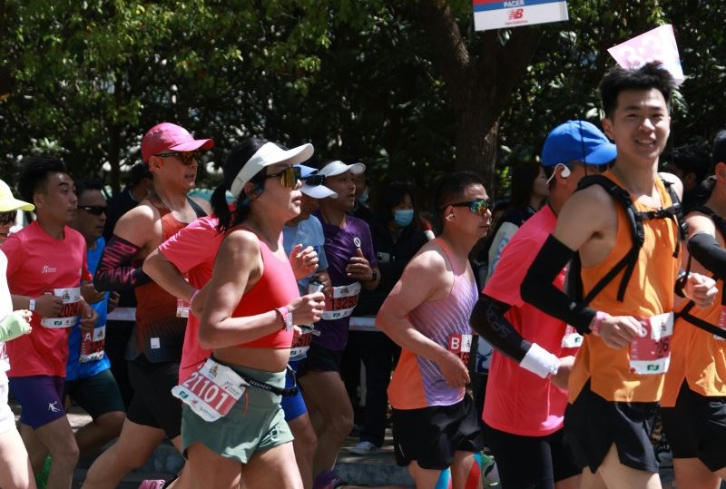 Energetic marathon runners participating in an outdoor race under a clear sky.