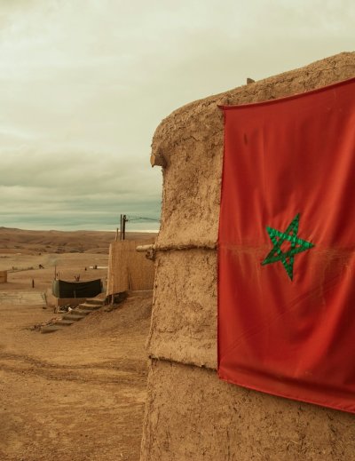 Moroccan flag hangs on a clay building in desert landscape
