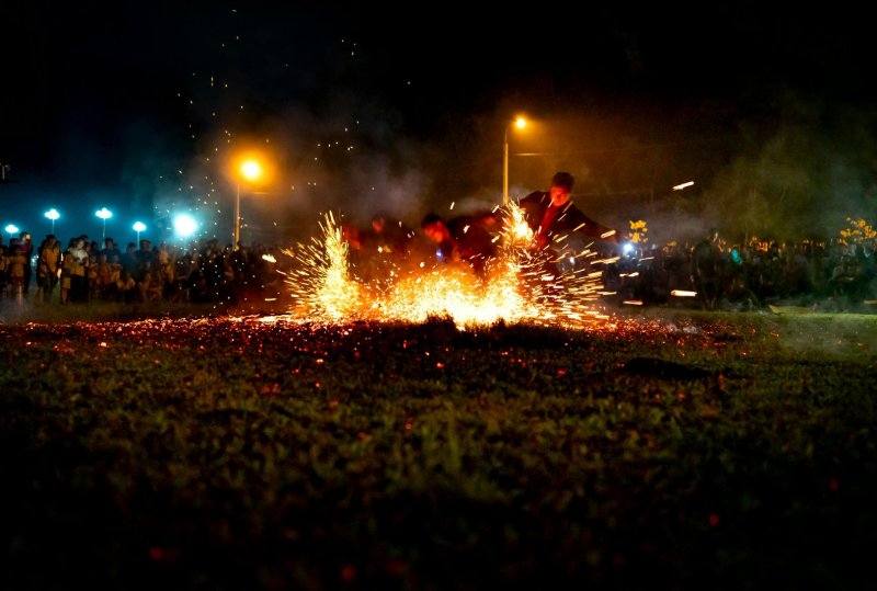 Group of fearless male dancers performing in sparkling bright lights of fire among crowd of people