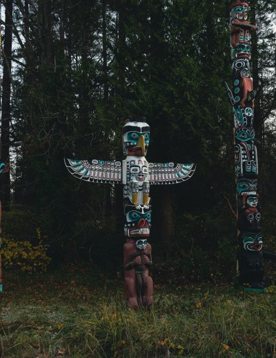 group of totem poles standing in the forest