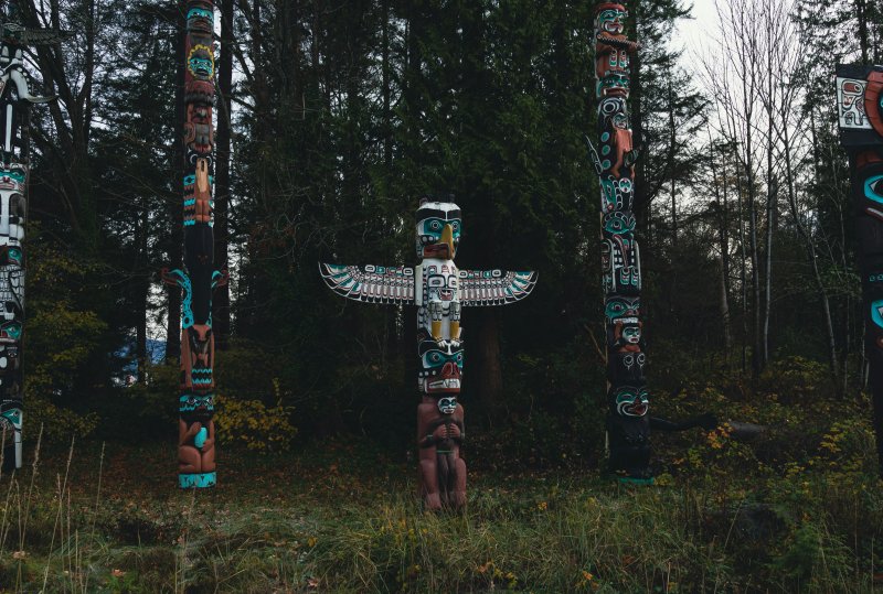 group of totem poles standing in the forest